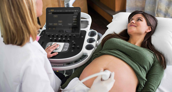 una mujer acostada en una cama con un m&eacute;dico